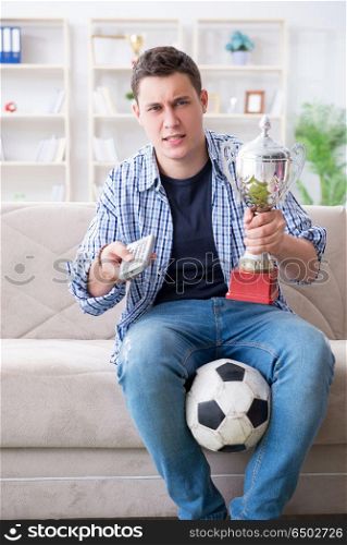 Young man student watching football at home