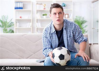 Young man student watching football at home