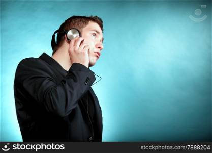 Young man student with headphones listening to music blue background