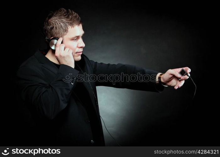 young man student with headphones use mp3 player listening to music black grunge background