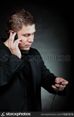 young man student with headphones use mp3 player listening to music black grunge background