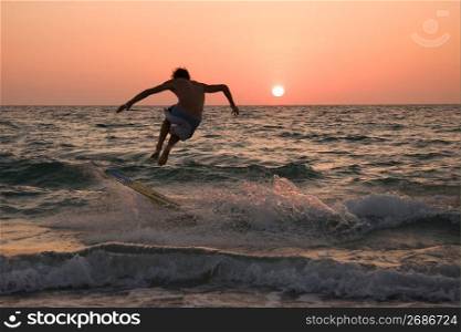 Young man surfing at sunset