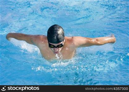 Young man swimming the butterfly stroke in a swimming pool