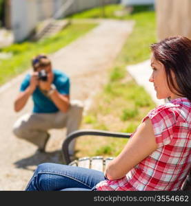 Young man take photo of his girlfriend sitting park bench