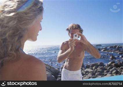Young man taking a photograph of a young woman