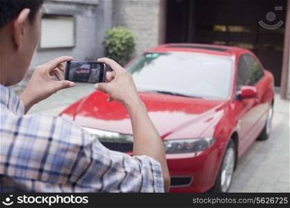 Young Man Taking a Picture of His Car