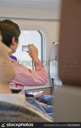 Young Man Taking a Picture Out Airplane Window
