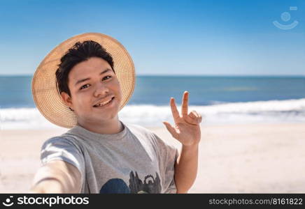 Young man taking a selfie portrait on the beach, handsome boy taking a selfie on the beach