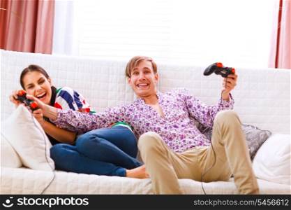 Young man taking joystick from his winning girlfriend while playing console&#xA;