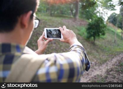 Young man taking photo with his phone of the mountain view