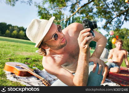 Young man taking photographs at park party
