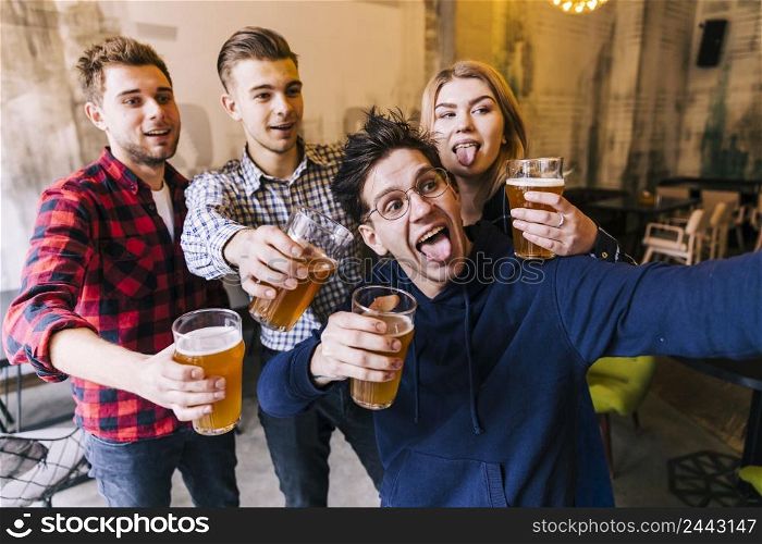 young man taking selfie mobile phone with his friends holding glasses beer