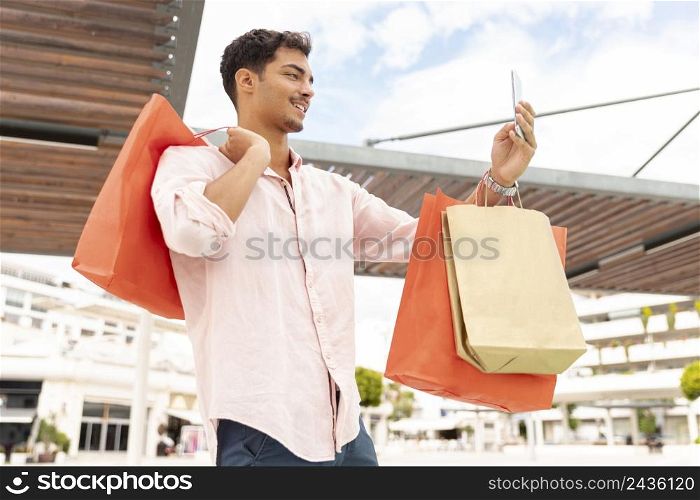 young man taking selfie with shopping bags