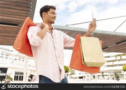 young man taking selfie with shopping bags