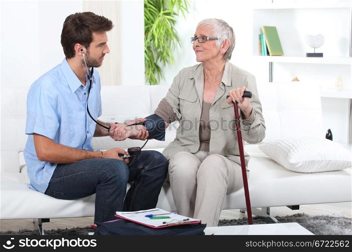 Young man taking the blood pressure of an older lady