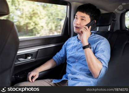 young man talking on mobile phone while sitting in the back seat of car