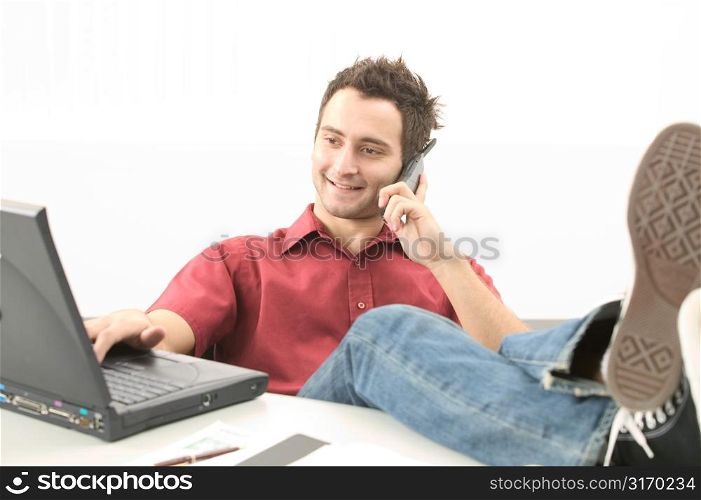 Young Man Talking on Phone And Working on Laptop