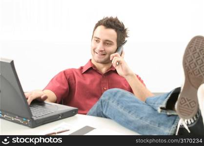 Young Man Talking on Phone And Working on Laptop