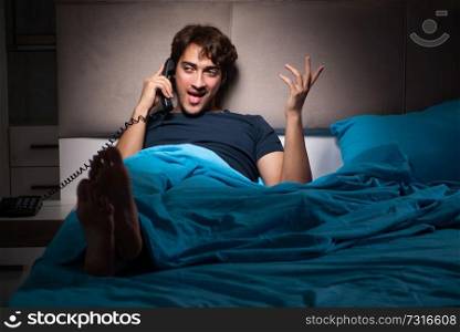 Young man talking on phone in bed