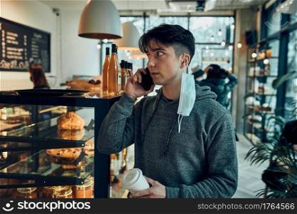 Young man talking on the phone at cafe, having a important phone call, answering call, chatting by mobile phone with colleague while spending time in a cafe and drinking coffee