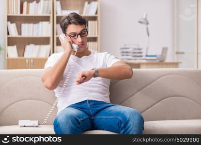 Young man talking on the phone lying in couch