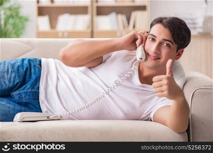 Young man talking on the phone lying in couch