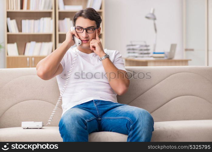 Young man talking on the phone lying in couch