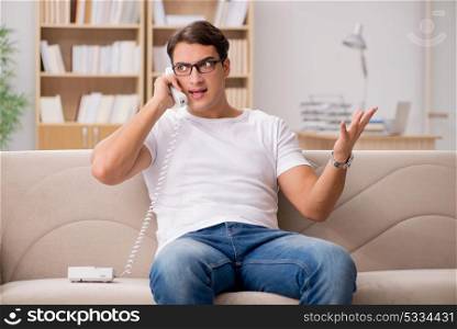 Young man talking on the phone lying in couch