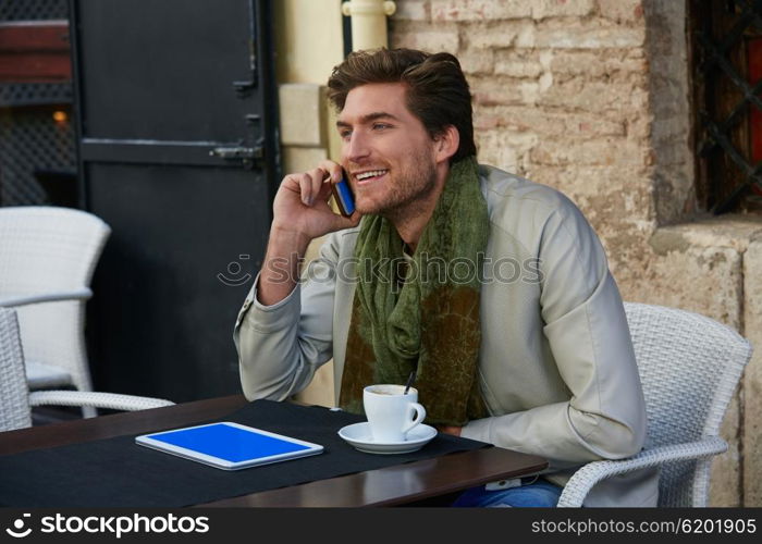 Young man talking smartphone phone in an cafe outdoor sitting having some coffe