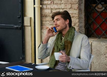Young man talking smartphone phone in an cafe outdoor sitting having some coffe