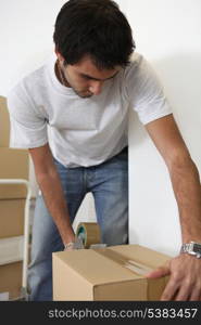 Young man taping shut a cardboard box