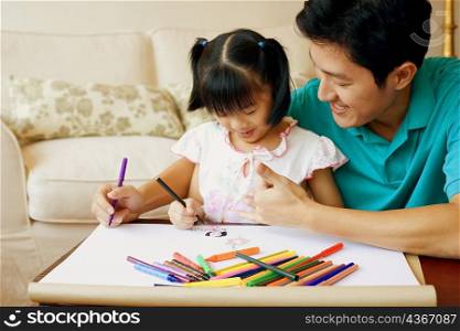 Young man teaching his daughter to color