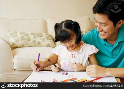 Young man teaching his daughter to color