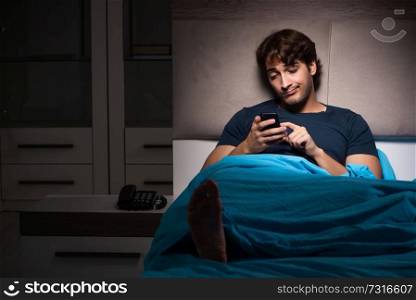 Young man texting on mobile late at night
