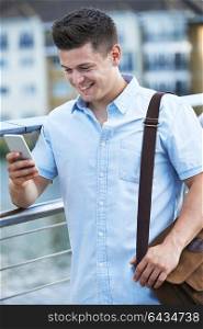 Young Man Texting On Mobile Phone Walking To Work