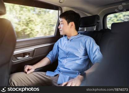 young man thinking and looking view out of window while sitting in the back seat of car