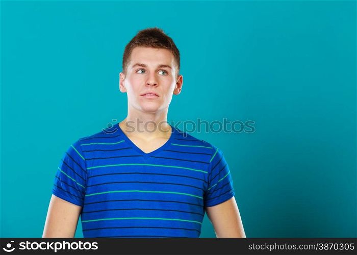 Young man thinking, thoughtful face expression on blue