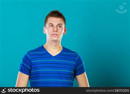 Young man thinking, thoughtful face expression on blue