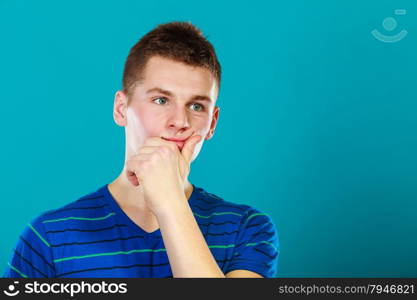 Young man thinking, thoughtful face expression on blue