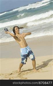 Young man throwing a ball on the beach