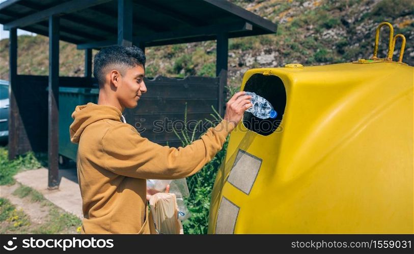 Young man throwing plastic garbage to container. Man throwing garbage to container