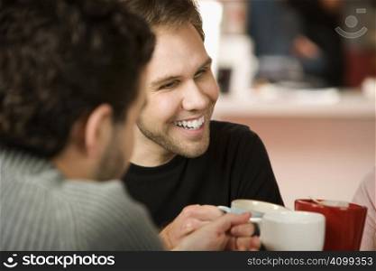 Young man toasting friends with coffee cups