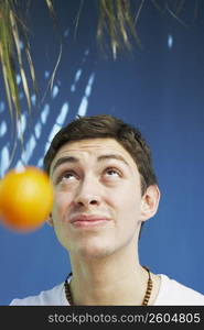 Young man tossing an orange