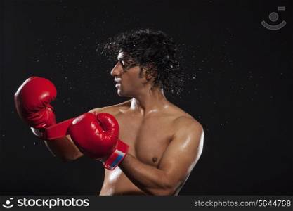Young man tossing hair while wearing boxing gloves