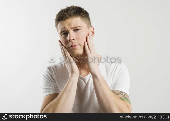 young man touching his cheeks with two hands against white background