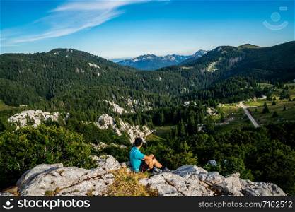 Young man traveler and explorer travels in the forest and mountain nature landscape hiking across Zavizan Gora in Croatia.
