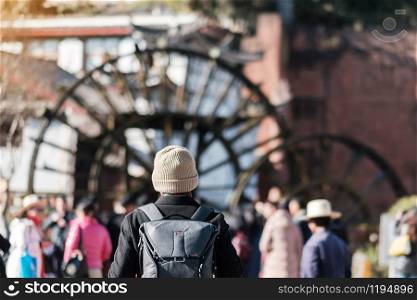 young man traveler traveling at Giant Water Wheels in Lijiang Old Town, landmark and popular spot for tourists attractions in Lijiang, Yunnan, China. Asia travel concept