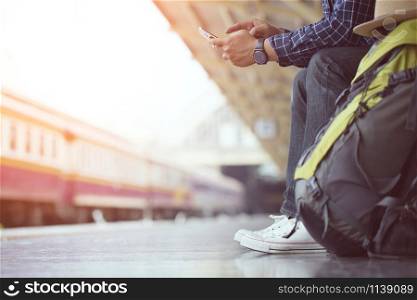 Young man traveler with backpack and Travel equipment sit use phone on public car. Travel concept.