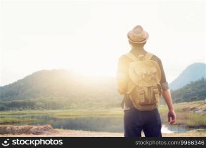 Young Man Traveler with backpack relaxing outdoor. Summer vacations and Lifestyle hiking concept. Retro filter effect, selective focus.