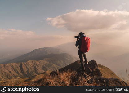 Young man traveler with backpack taking a photo on mountain, Adventure travel lifestyle concept